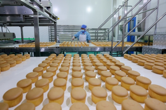 在烘焙车间，工人正在查看糕点成品合格情况。梁洁摄